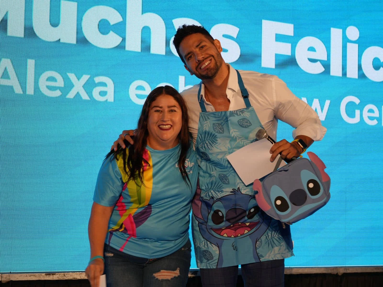 Rodolfo y una participante sonríen sobre el escenario.