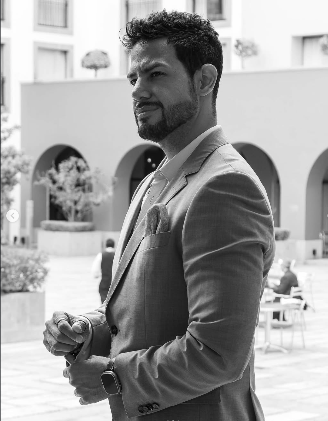 Rodolfo Popoca ajusta la manga de su saco en un patio, retratado en blanco y negro.